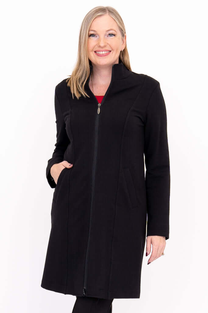 Smiling woman modeling black zip-up princess seam coat, hand in pocket