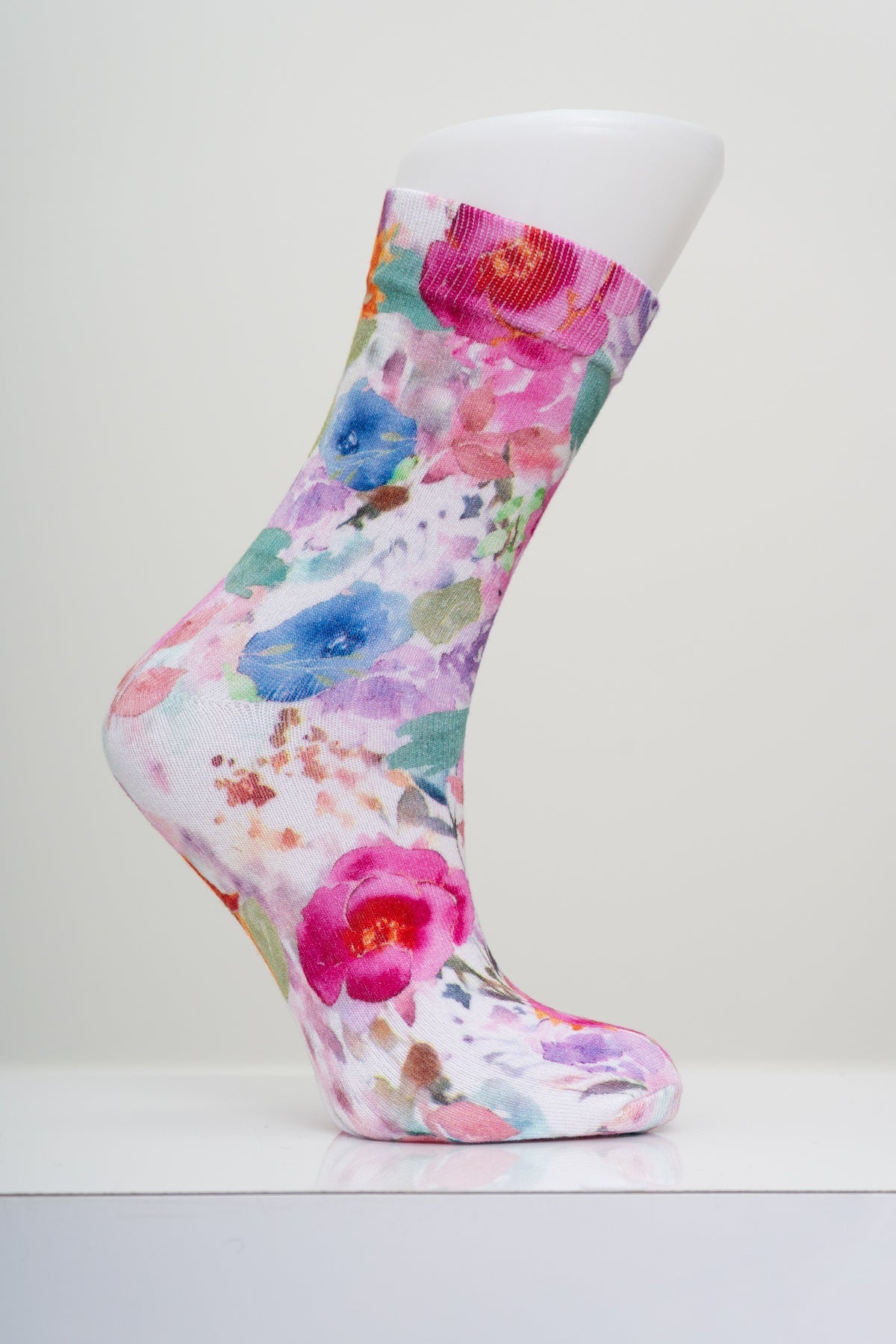 Pink and blue watercolor floral bouquet patterned crew sock shown on a white display mannequin foot form.