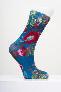 Teal blue crew sock with a colorful floral and botanical print on a white mannequin foot form against light gray.