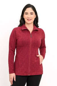 Smiling woman posing in a red patterned bamboo zip-up jacket with her hand on her hip, front-facing view.