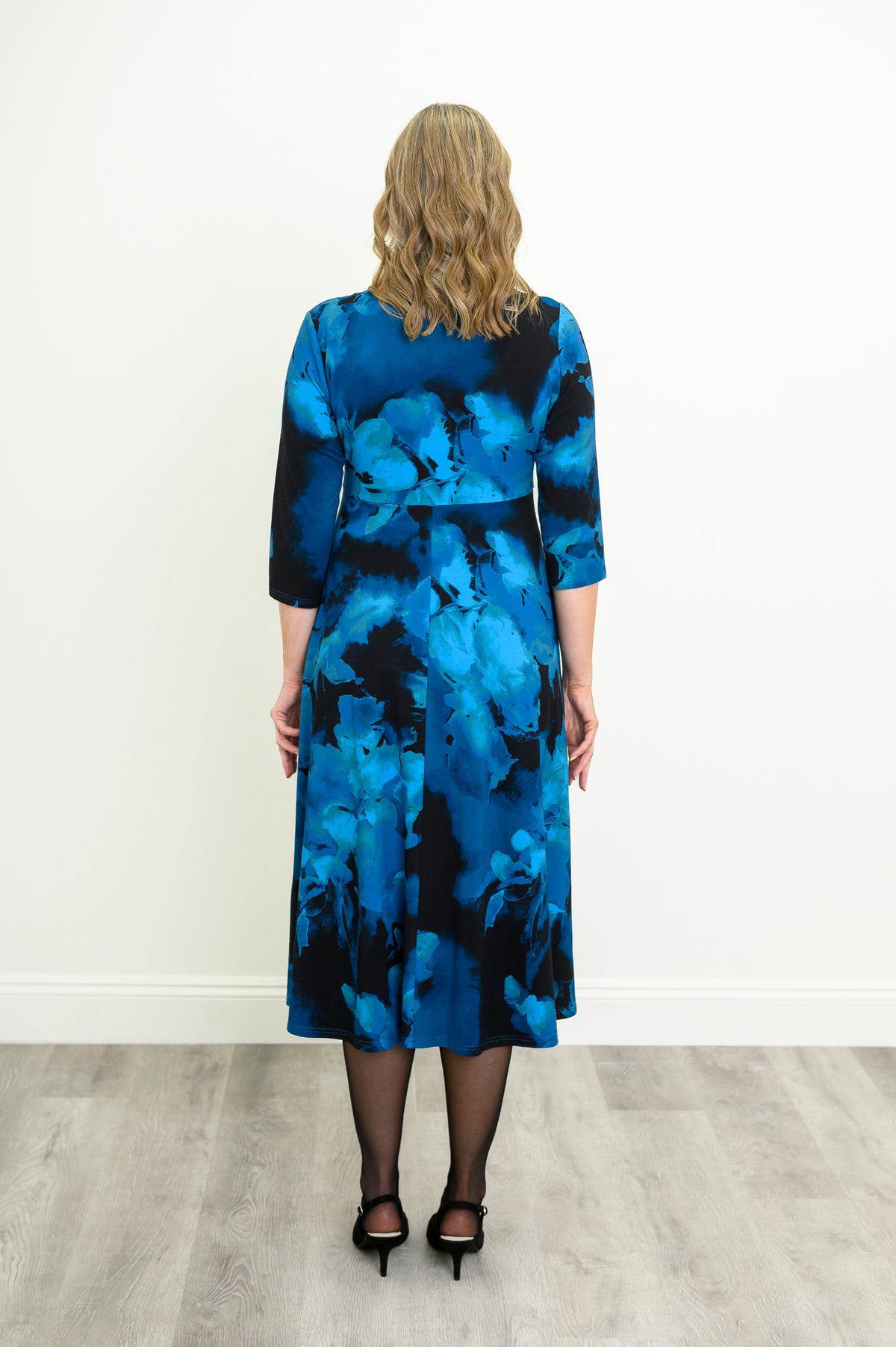 Rear view of an indigo patterned A-line midi dress highlighting the fluid skirt and full coverage.