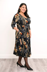 Side profile view of a woman wearing a black and orange floral print midi dress showing the relaxed drape.