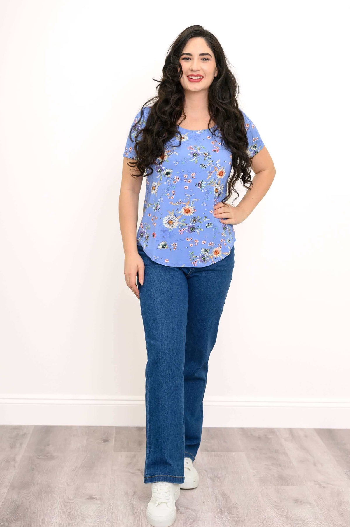 Front view of woman standing in a blue floral tee and jeans