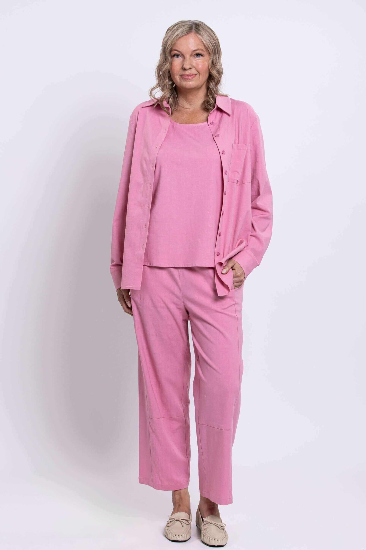 Front standing view of a woman in a coordinated pink shirt, tank, and pants outfit