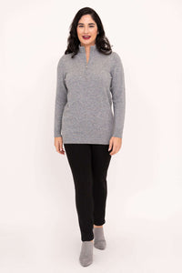 Woman standing in a grey half-zip sweater and grey shoes