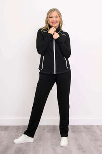 Woman standing with hands near collar, modeling black Hartford Utility Vest and pants