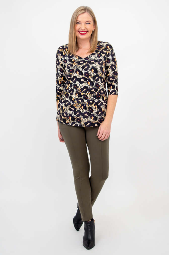 Woman standing in leopard print long sleeve top and olive pants