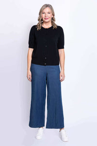 Front view of a woman wearing a black short-sleeve cardigan and blue pants, standing