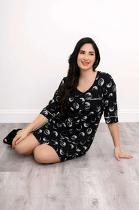 Woman sitting on the floor wearing a black moon phase pattern sleepshirt