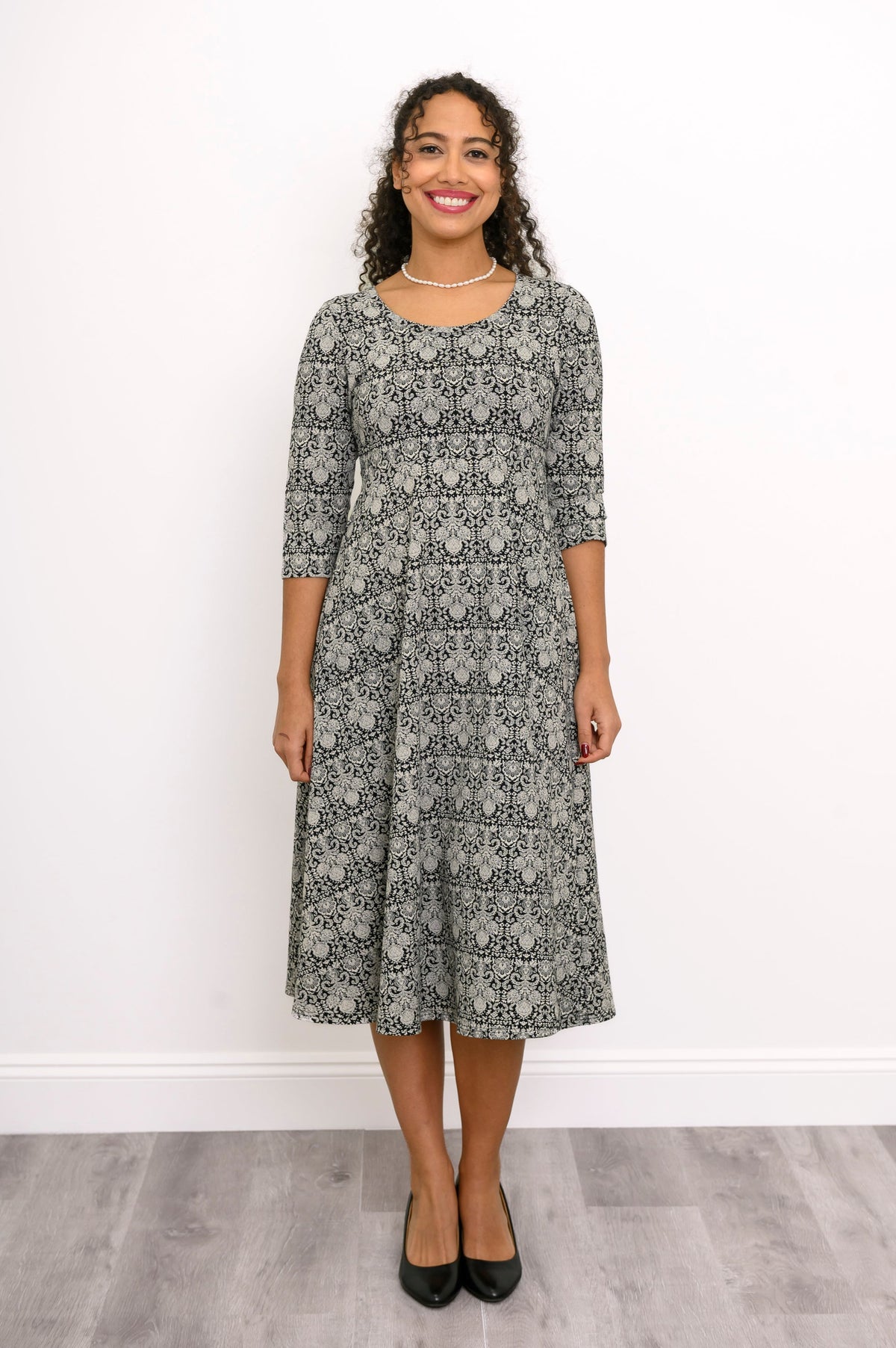 Straight front shot of an everyday grey floral print dress with a scoop neck and three-quarter sleeves.