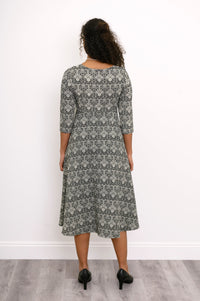 Back view of a woman wearing a grey patterned midi dress with a clean, seamless finish across the shoulders.