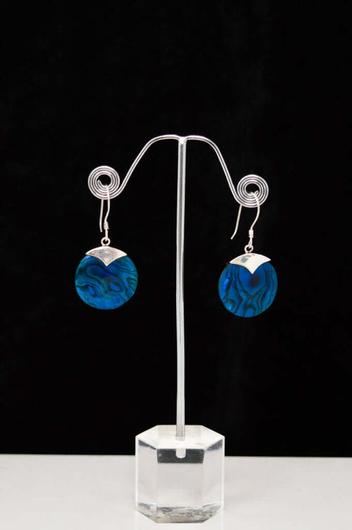 Pair of sterling silver drop earrings with blue abalone shell discs displayed on a stand