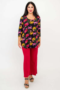 Full body front view of model in black top with floral print and red pants, standing straight