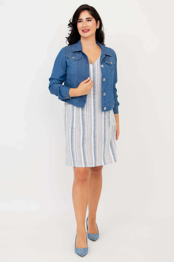 Woman in a striped shift dress layered with a blue denim jacket and blue heels