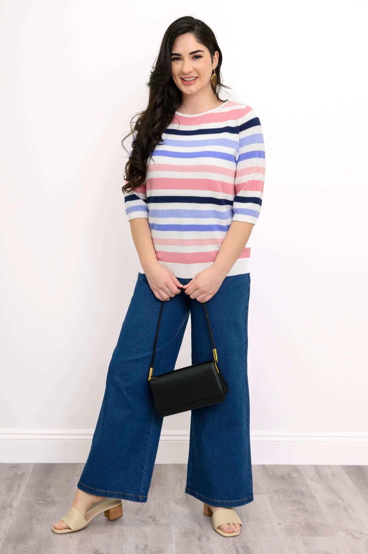 Woman modeling striped cotton sweater with a black handbag and wide-leg jeans