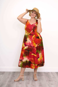 Woman wearing sleeveless sunset-inspired midi dress and sun hat, striking a cheerful pose