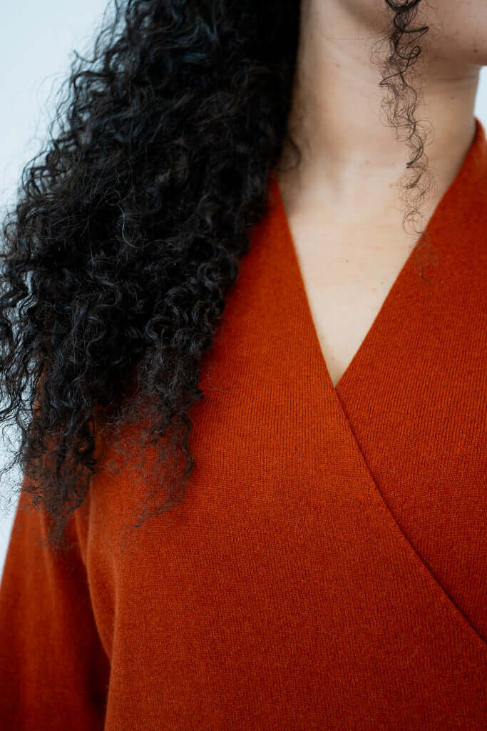 Close-up detail of surplice neckline on rust sweater