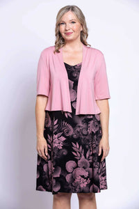 Woman wearing a black dress with pink floral print and a light pink cardigan