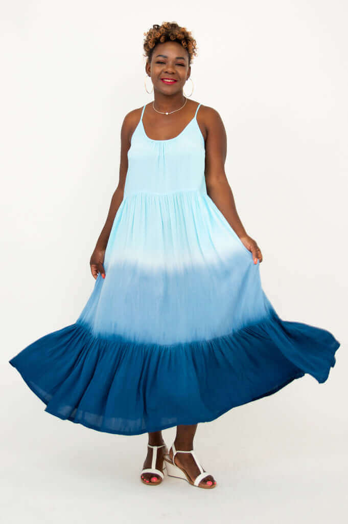 Woman swirling in a blue ombre maxi dress, highlighting wide hemline