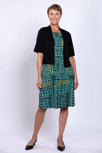 Woman wearing teal and yellow sleeveless dress and black cardigan, posing