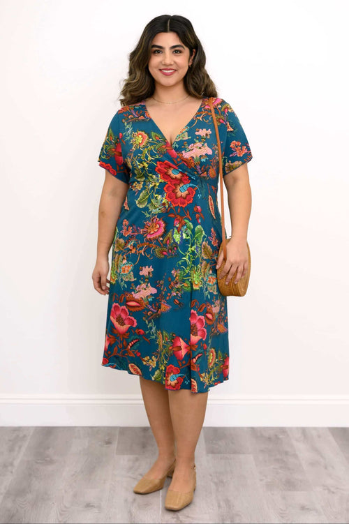 Woman wearing a teal bamboo dress with bold red and pink floral print, standing front-facing