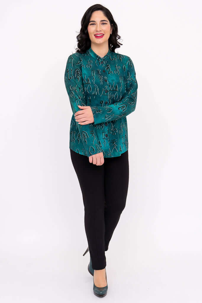 Smiling woman modeling a teal blouse with symbol print, front view with arms crossed
