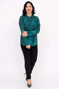 Smiling woman modeling a teal blouse with symbol print, front view with arms crossed
