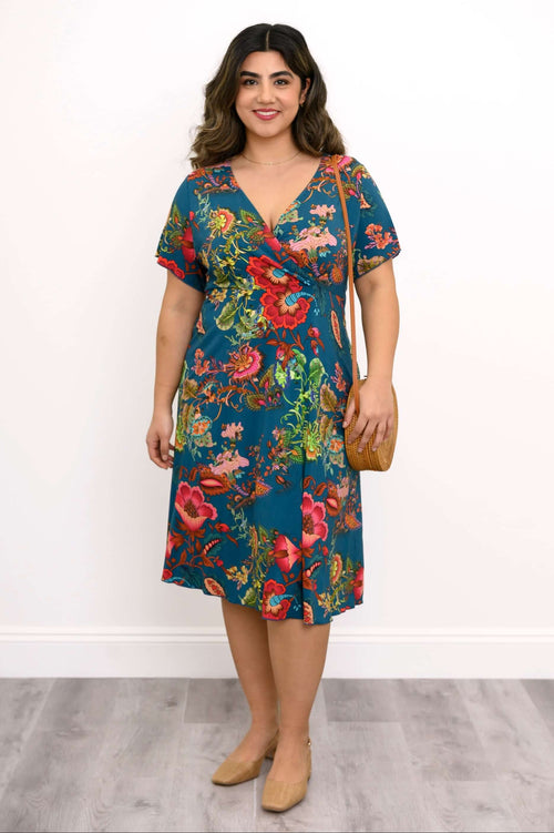 Model wearing a teal dress with vibrant floral print and cross-over bodice, front view