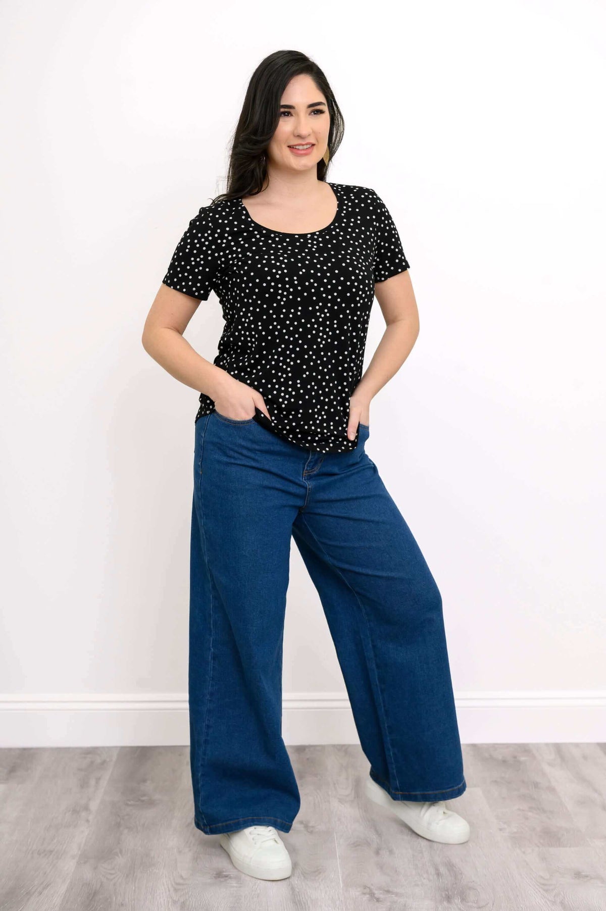 Full body view of model in black polka dot Tessa Tee with blue wide-leg jeans