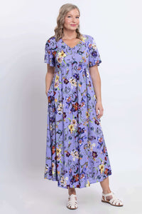 Three-quarter front view of woman in violet floral flutter sleeve maxi dress