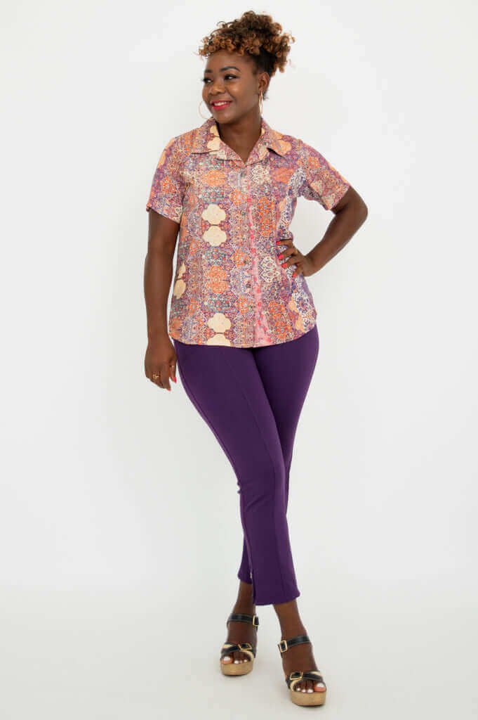 Three-quarter front view of woman in boho mosaic shirt and purple pants