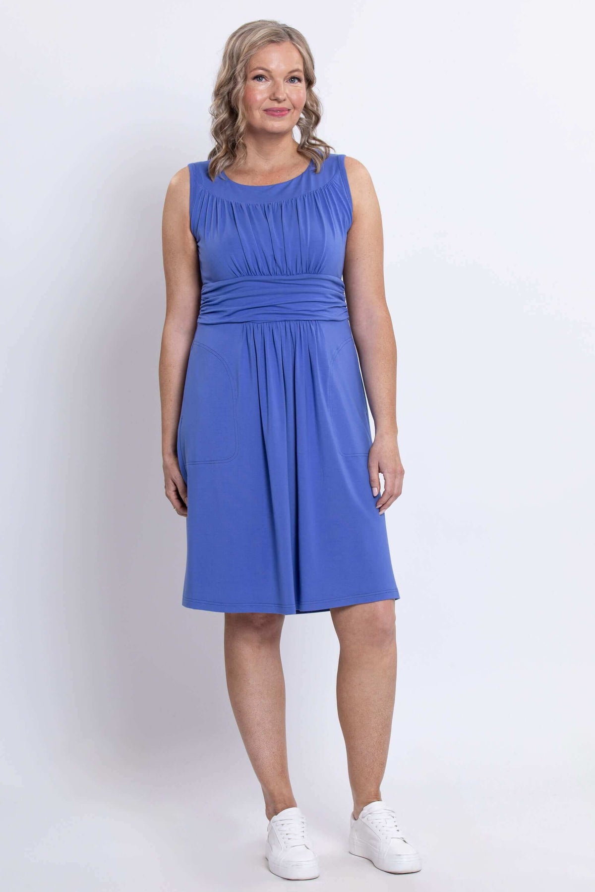 Three-quarter front view of woman wearing violet sleeveless ruched dress with waistband