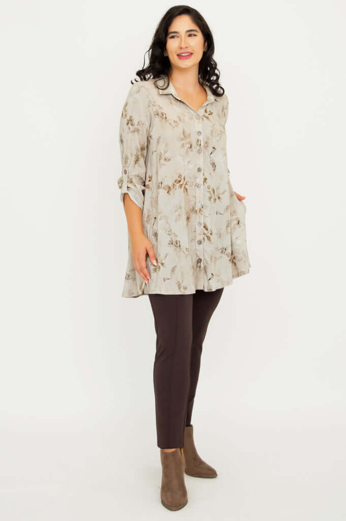 Three-quarter front view of woman in button-up floral tunic shirt and brown pants