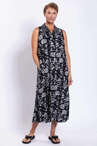 Three-quarter front view of woman in sleeveless floral black and white dress with pockets