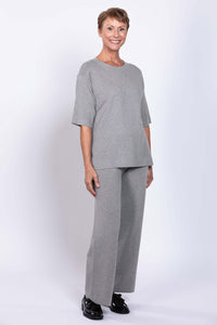 Three-quarter front view of a woman modeling a light grey sweater set with relaxed fit