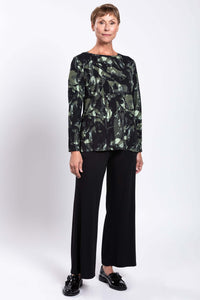 Three-quarter front view of a woman wearing a bamboo print top with black flared pants