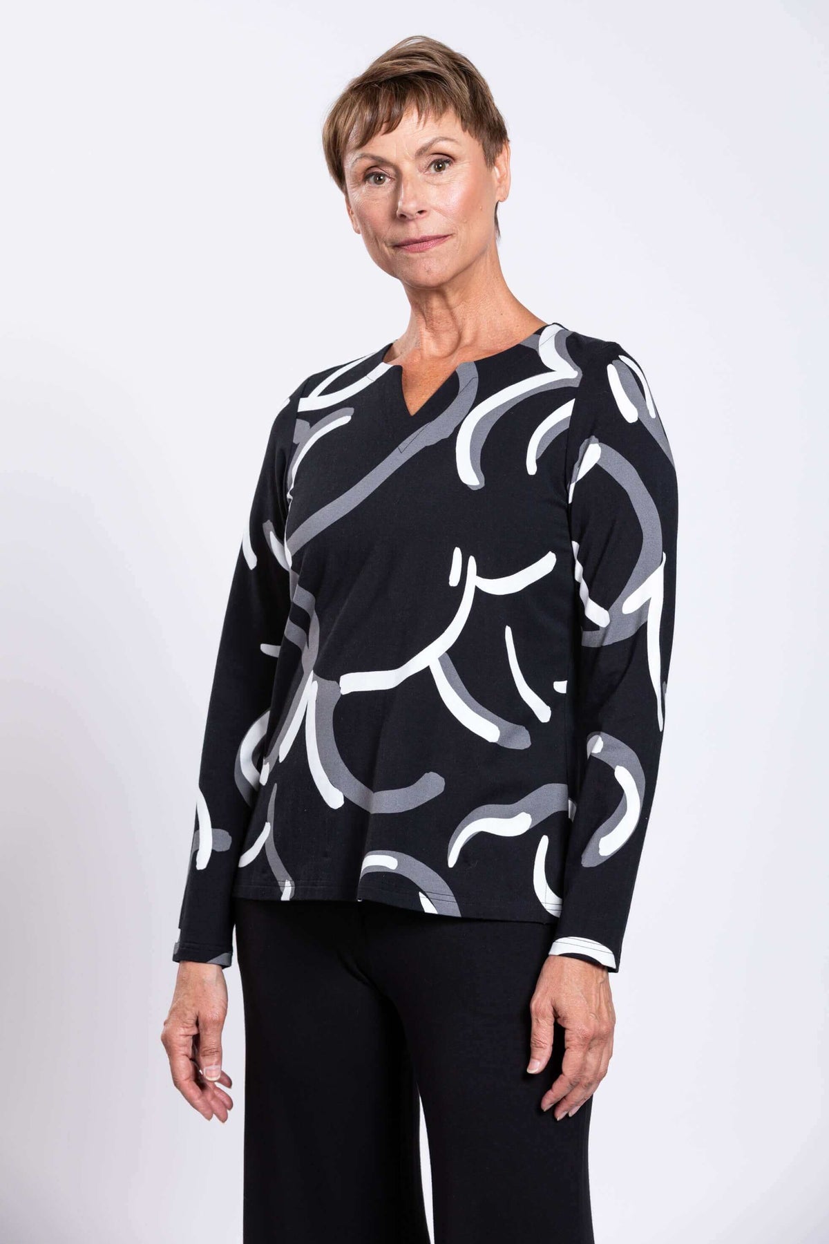 Three-quarter front view of model in black top with abstract white and grey swirls