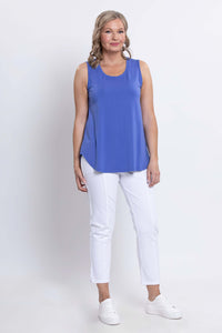 Three-quarter front view of woman in blue sleeveless tank top and white pants