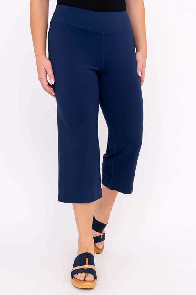 Three-quarter front view of navy blue yoga capri pants on a model