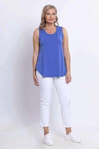 Three-quarter front view of a woman in a blue bamboo tank top and white pants