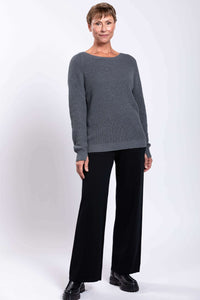 Three-quarter front view of woman in grey sweater and black wide-leg pants