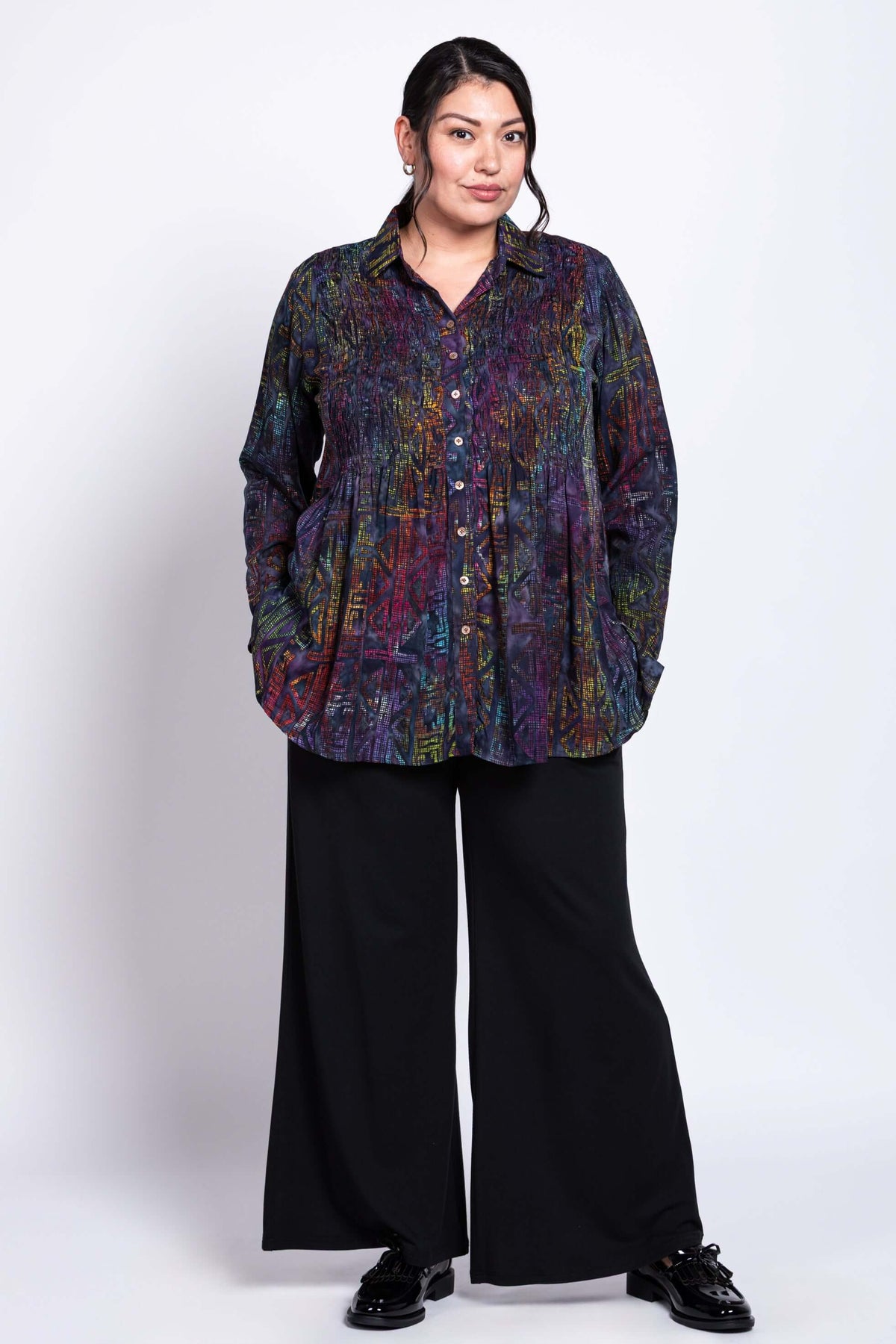 Three-quarter view of model in Cindy rainbow geometric shirt and black wide-leg pants