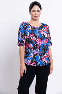 Three-quarter front view of woman wearing round-neck blouse in blue and pink leaf print