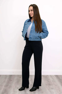 Three-quarter view of woman wearing The Gerry jean jacket and black trousers