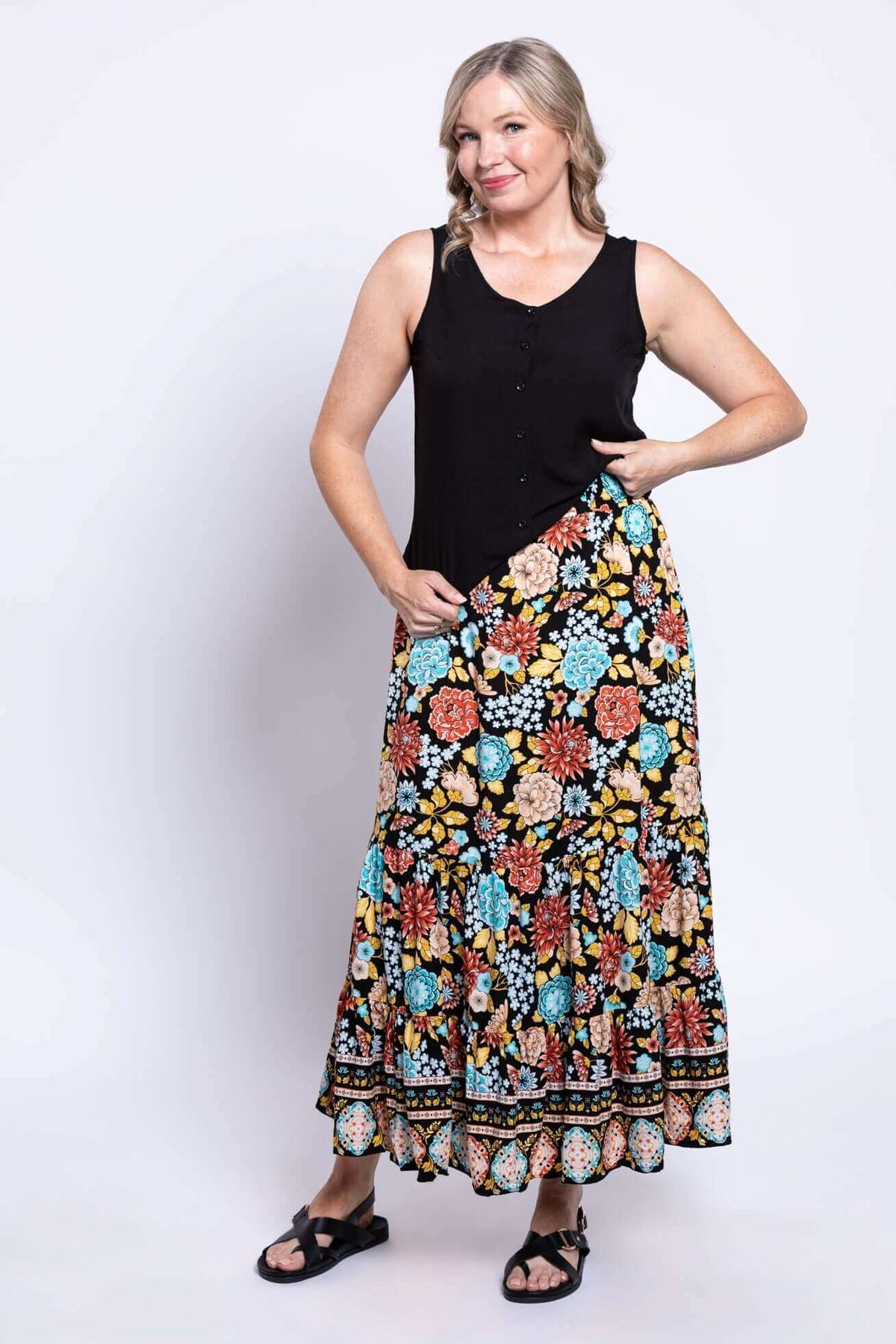 Three-quarter view of a woman modeling a colorful floral tiered maxi skirt and black top