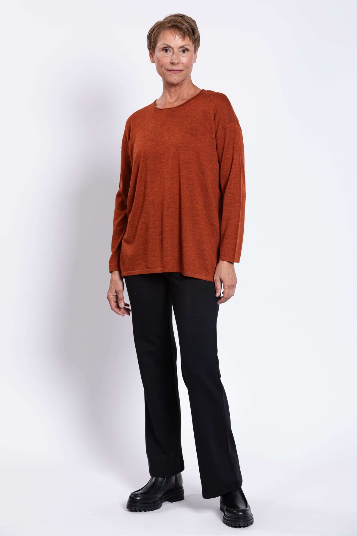 Three-quarter view of woman in rust red Merino wool sweater with relaxed fit