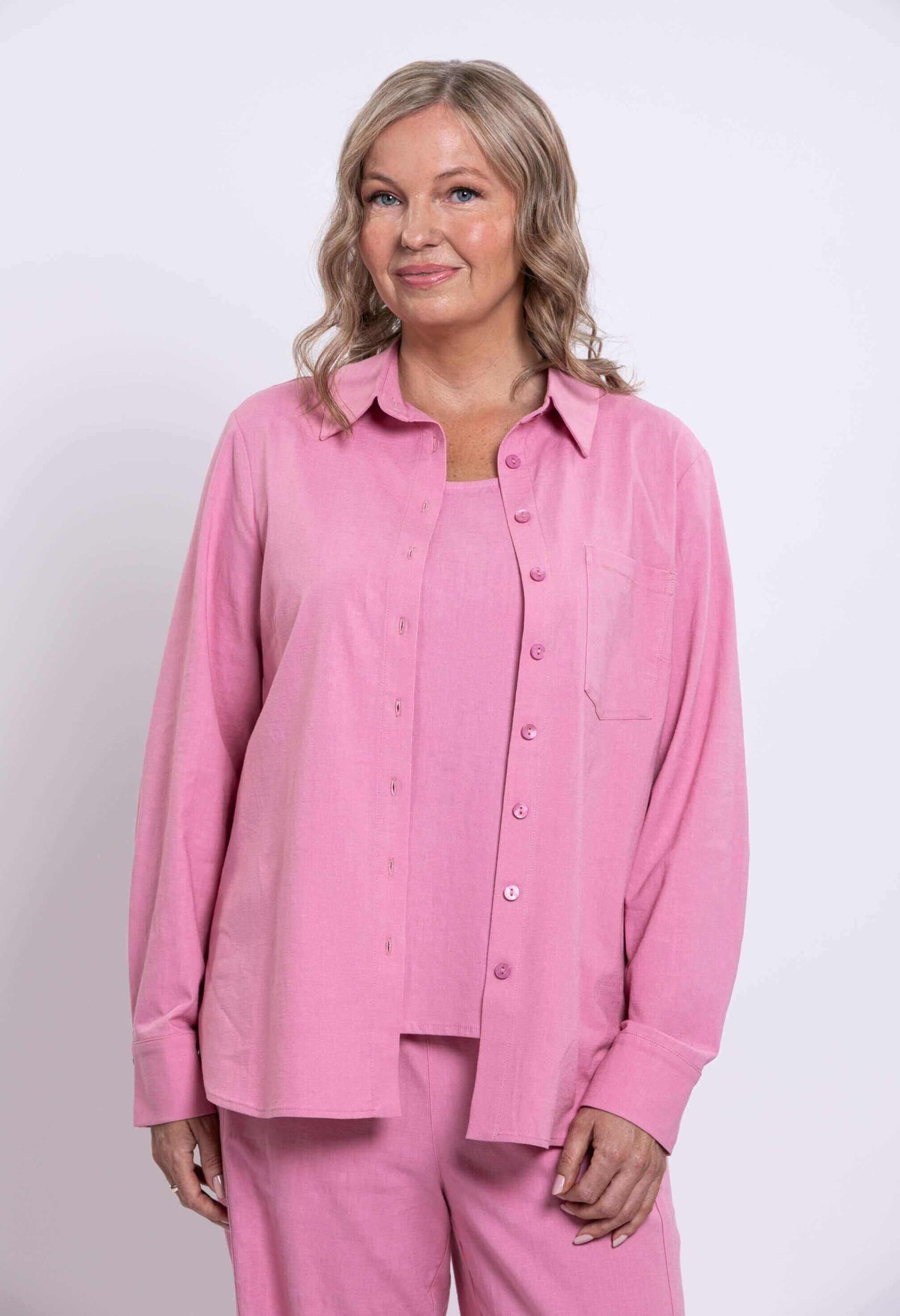 Three-quarter front view of a woman in a pink relaxed shirt with breast pocket