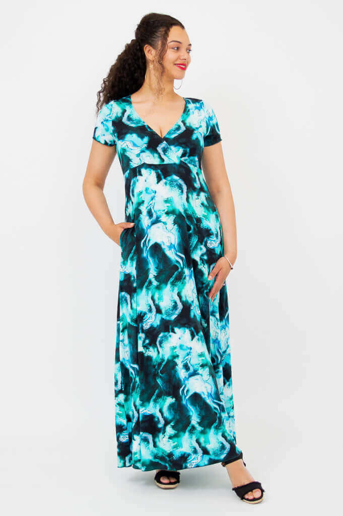Three-quarters view of a woman in a blue green marble print bamboo maxi dress with pockets