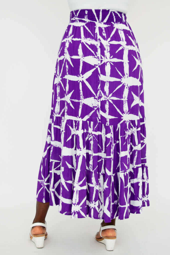 Rear view of a model wearing the Tibby maxi skirt in purple and white with tiered design