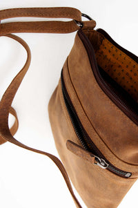 Angled top view of leather pouch displaying front zipper and adjustable strap